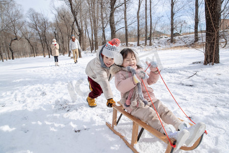 欢乐家庭摄影照片_欢乐家庭在雪地上玩雪橇