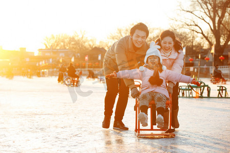 冬季亲情摄影照片_一家三口在滑冰场坐冰车玩耍