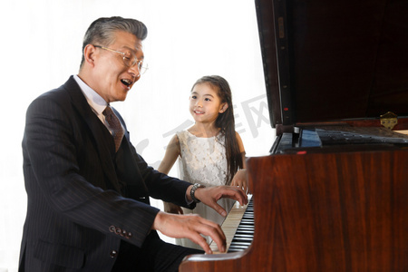 男人唱歌摄影照片_祖父和孙女一起弹钢琴