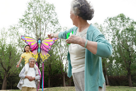 风筝摄影照片_老年夫妇带着孙女在公园里放风筝