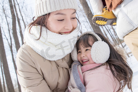 年轻啊妈妈和女儿在雪地里玩耍