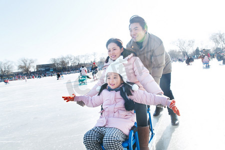 人车冬季摄影照片_快乐的一家三口坐冰车玩耍