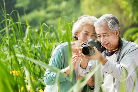 立即报名拍照按钮摄影照片_老年夫妇在公园里拍照