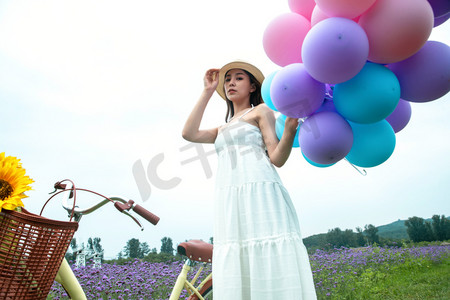 美女拿着花摄影照片_青年女人在花海里拿着气球