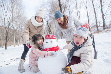 雪人摄影照片_欢乐家庭在雪地里堆雪人