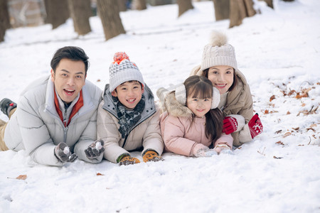 趴在雪地里玩耍的快乐家庭