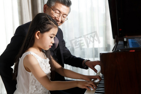 老年人音乐摄影照片_祖父和孙女一起弹钢琴