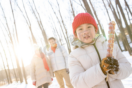 雪树林摄影照片_雪地上小男孩拿着糖葫芦