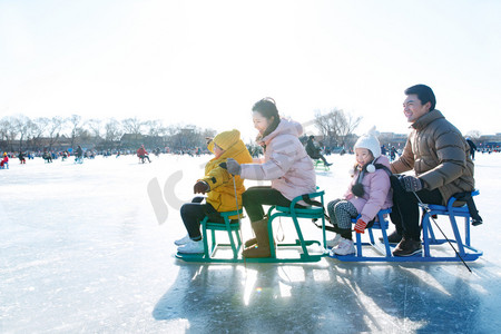 人车冬季摄影照片_快乐的一家人坐冰车玩耍