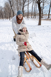 雪树林摄影照片_青年夫妇在雪地上玩雪橇