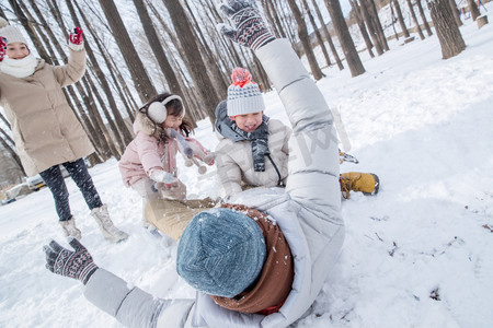 儿童躺着摄影照片_雪地里打雪仗的快乐家庭