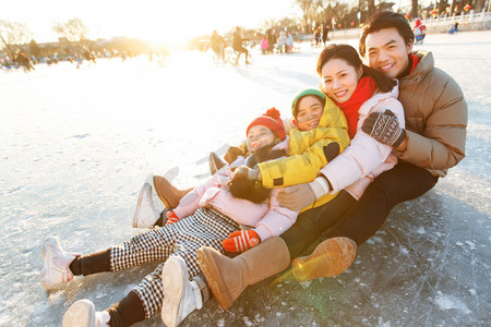 冬季亲情摄影照片_快乐的一家四口坐在冰面上玩耍