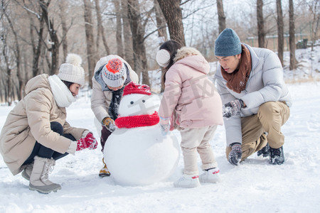 雪人摄影照片_欢乐家庭在雪地里堆雪人