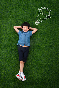 灯泡插画摄影照片_可爱的小男孩躺在草地上