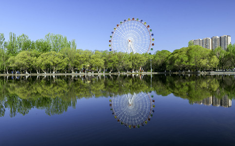 游乐园设施摄影照片_公园游乐设施上午树木湖水夏季素材摄影图配图