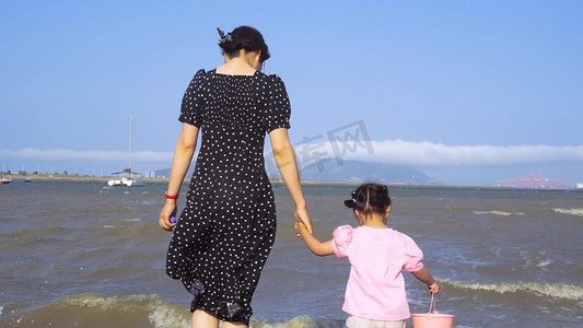小孩海边摄影照片_夏季海边度假游玩美女牵手小孩海边玩耍