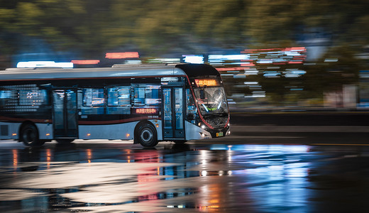 城市的夜晚摄影照片_雨天夜晚行驶的公交汽车摄影图配图