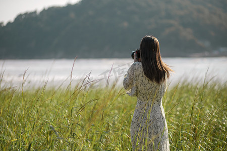 海边女子摄影照片_海边拍照的女子摄影图配图