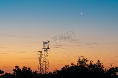 唯美的风景图摄影照片_清晨高压电输送塔上的月牙摄影图配图