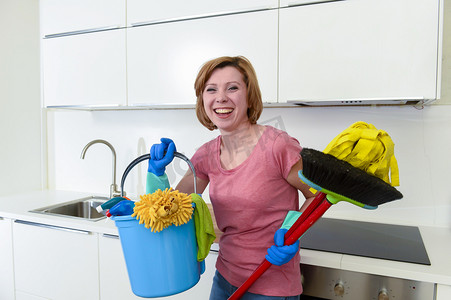 议定书摄影照片_在橡胶洗涤手套拿着清洗桶拖把和扫帚的红头发的女人