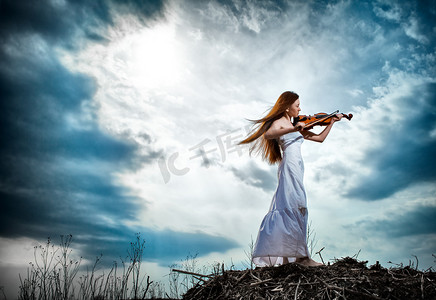 室外音乐摄影照片_红头发的女孩用室外的小提琴