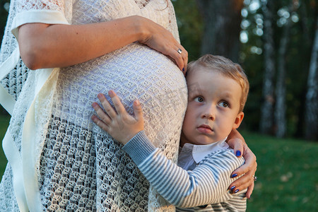 怀孕悲伤摄影照片_怀孕的妈妈和她的儿子