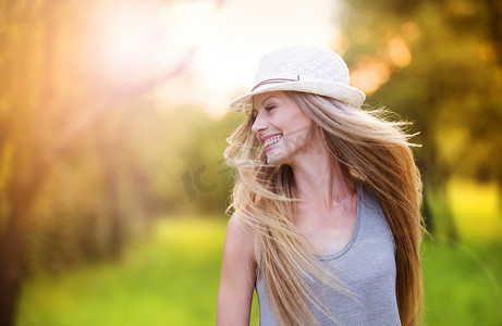 女人在笑在阳光明媚的公园里的白帽子