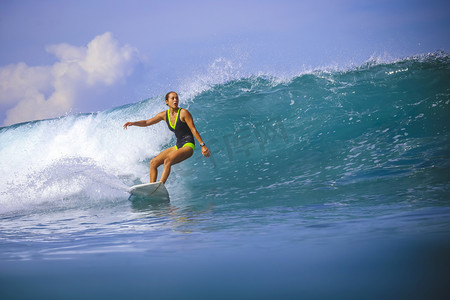 巴里島摄影照片_对令人惊异的蓝色波浪冲浪女孩