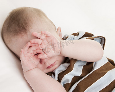 孩子眼睛摄影照片_揉着眼睛昏昏欲睡的白种人婴儿男孩