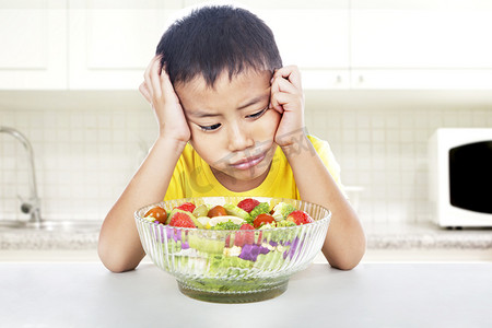 印度尼西亚摄影照片_不快乐的孩子吃沙拉