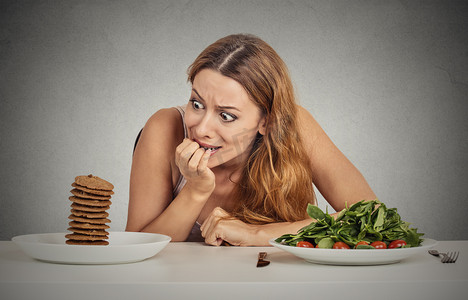 灰色磁带摄影照片_决定是否要吃健康的食物或甜饼干的女人她渴望