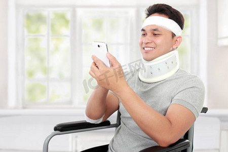 受伤的年轻人在轮椅上他 smartphione 播放