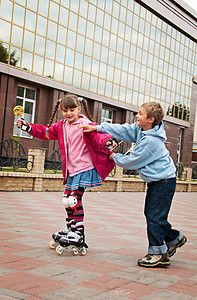 男孩旱冰摄影照片_一个女孩和一个男孩在公园散步。友谊和娱乐.