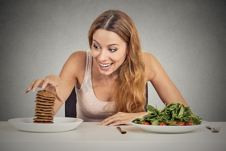 膳食脂肪摄影照片_决定是否要吃健康的食物或甜饼干的女人她渴望