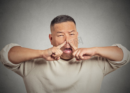 爆头的年轻人厌恶在脸上,捏的鼻子臭臭的