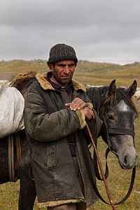 蒙古骑马摄影照片_男人牧羊犬牵马的缰绳