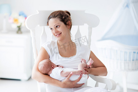 蓝色的婴儿摄影照片_年轻的母亲和刚出生的婴儿，在白色的卧室里