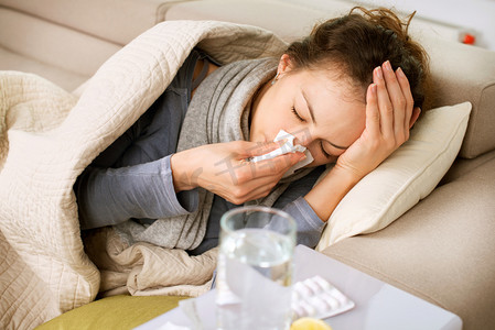 沙发摄影照片_生病的女人。流感。女人得了感冒。打喷嚏入组织