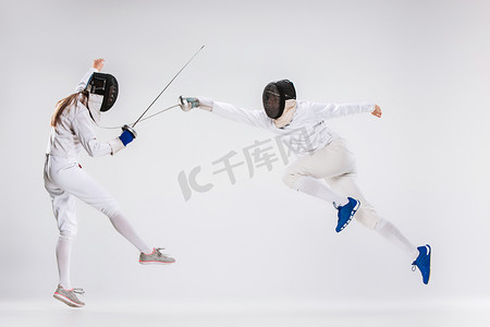 女子重剑摄影照片_男人和女人穿着击剑适合用刀攻击灰色练习