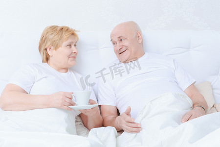 老年人躺床上摄影照片_对夫妇躺在床上进行交互