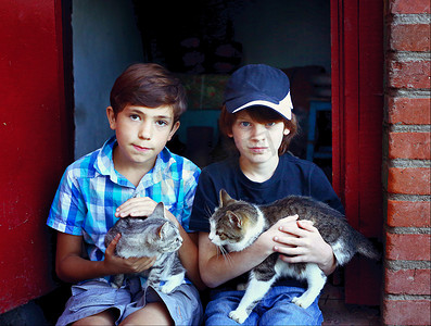 两个接近青春期男孩与猫在膝盖上