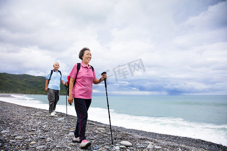 happy senior couple hiking on the coast beach