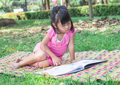 一个可爱的小女孩，读一本书的室外肖像