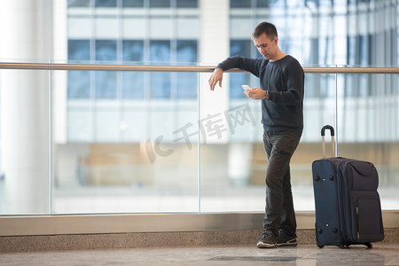 旅游征集摄影照片_年轻的旅行者在机场中使用智能手机 