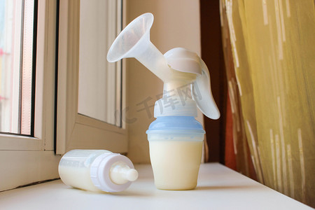breastpump摄影照片_吸奶器和瓶牛奶在窗台上