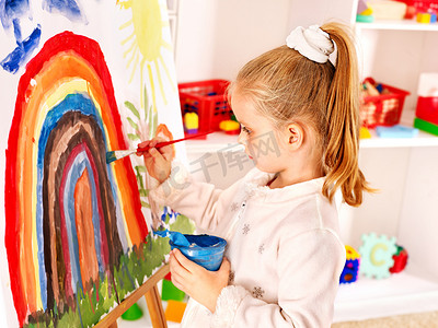 油漆图片摄影照片_儿童在画架上绘图.
