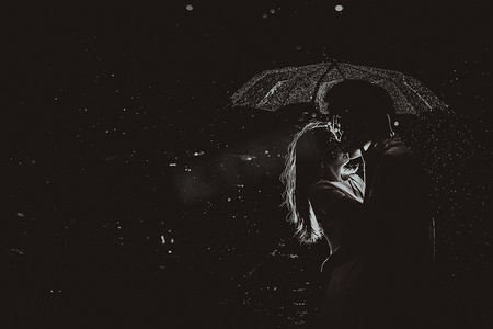Dramatic photo of a bride and groom in the night rain.