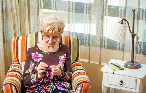 senior摄影照片_Senior woman knitting a wool quilt with patches