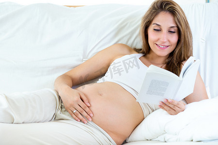 孕妇读一本书坐在沙发上.