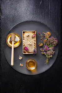 木托板摄影照片_蜂蜜和干的香草在深色背景上